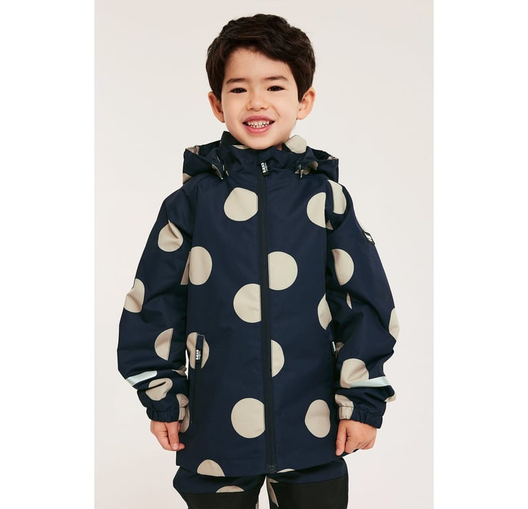 En pojke i matchande mörkblå skalkläder med stora, beiga prickar.