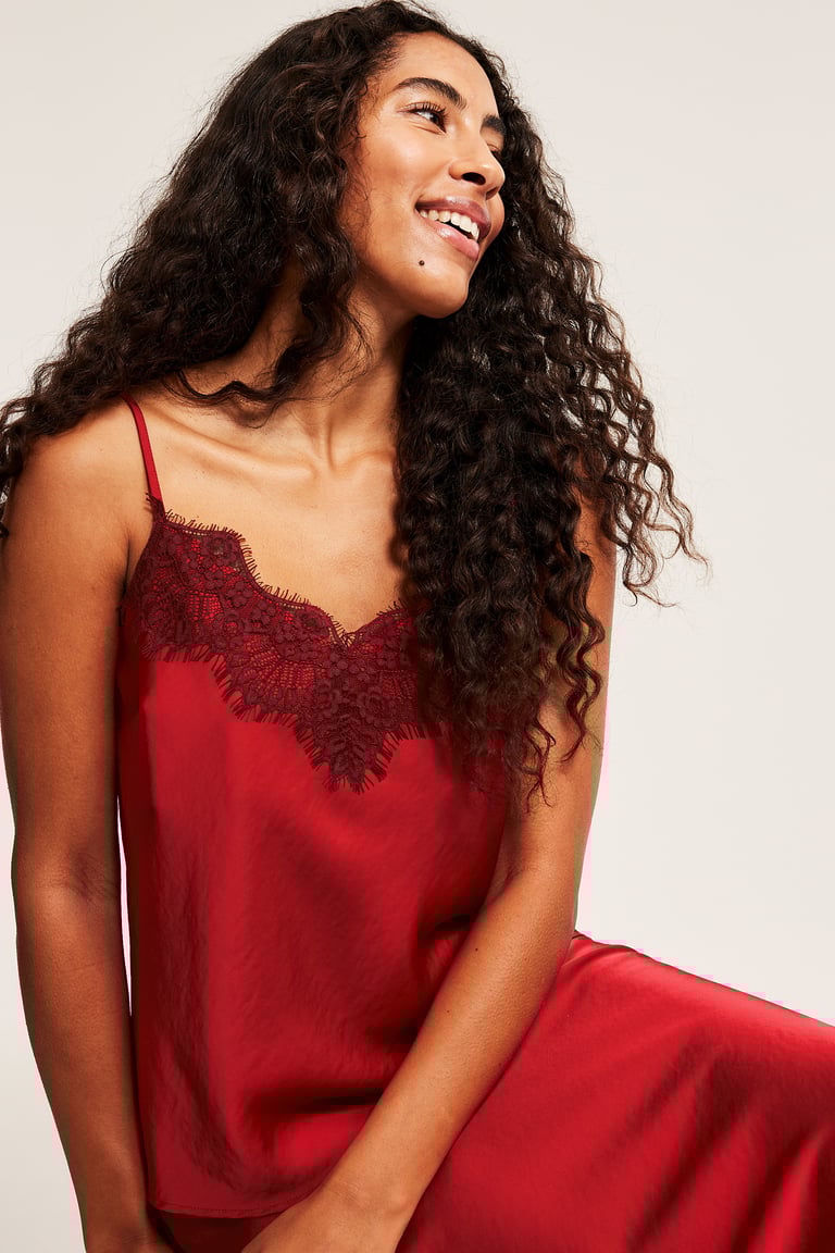 Nainen istuu punaisessa asussa, jossa on satiinimekko ja satiininen liivi.