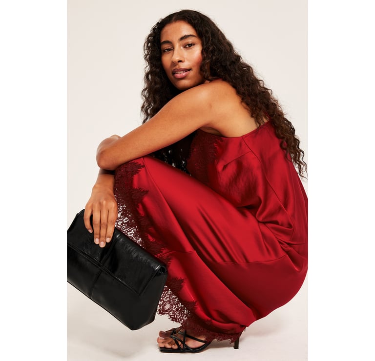 Kobieta siedząca w czerwonym zestawie z satynową spódnicą i satynowym topem