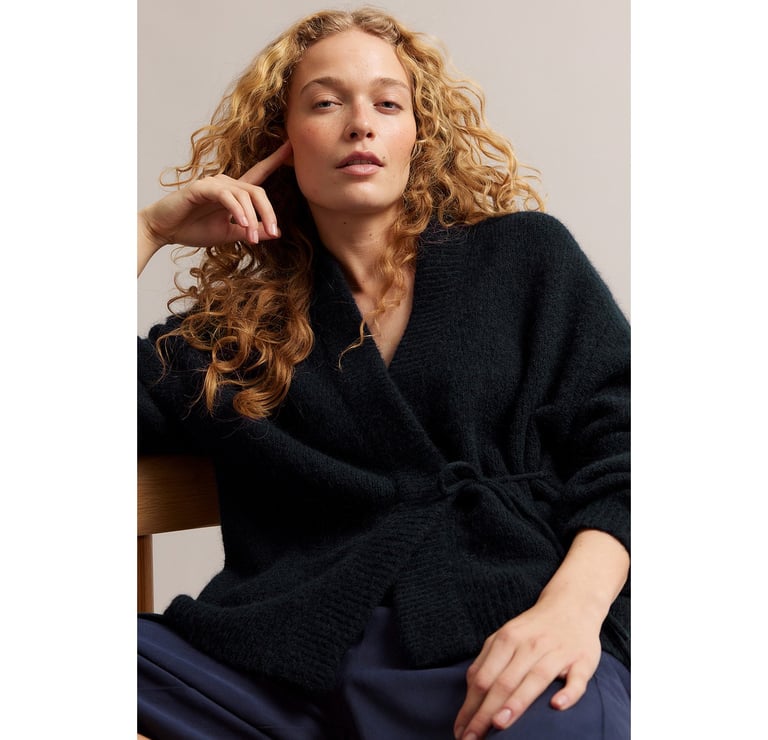 Kobieta w swetrze z mieszanki wełny z wiązaniem z boku.