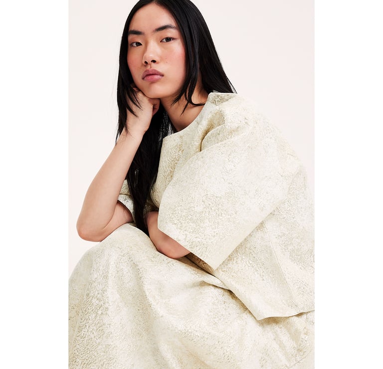 Nainen istuu jacquard-kuvioidussa lavasteessa