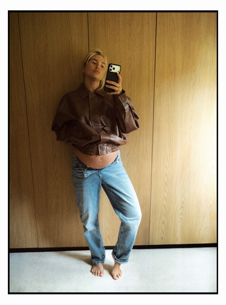 Kvinna i en brun skinnjacka och ett par uppknäppta ljusa jeans