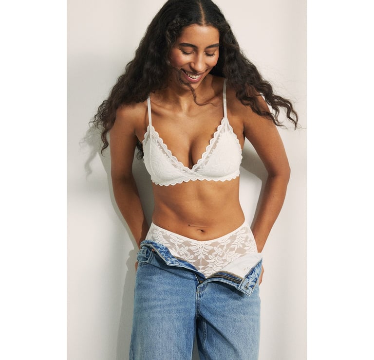 Kvinna iklädd ljusa underkläder och ett par öppna jeans