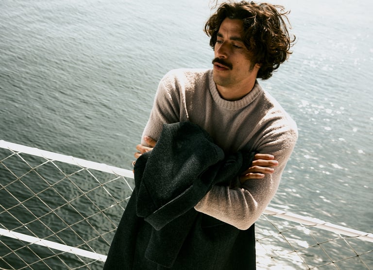 Man står på båt med jacka över armarna