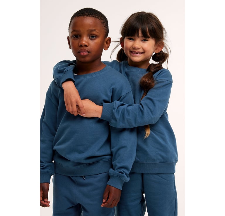 Poika ja tyttö samanlaisissa tummansinisissä collegepaidoissa.