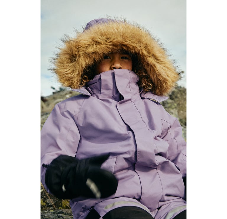 Dziewczyna na zewnątrz w fioletowych ogrodniczkach zimowych.
