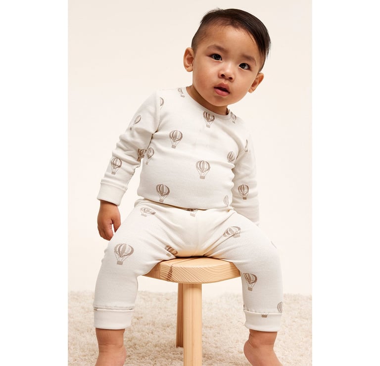 Dziecko siedzące na stołku ubrane w kombinezon i legginsy od Kappahl.