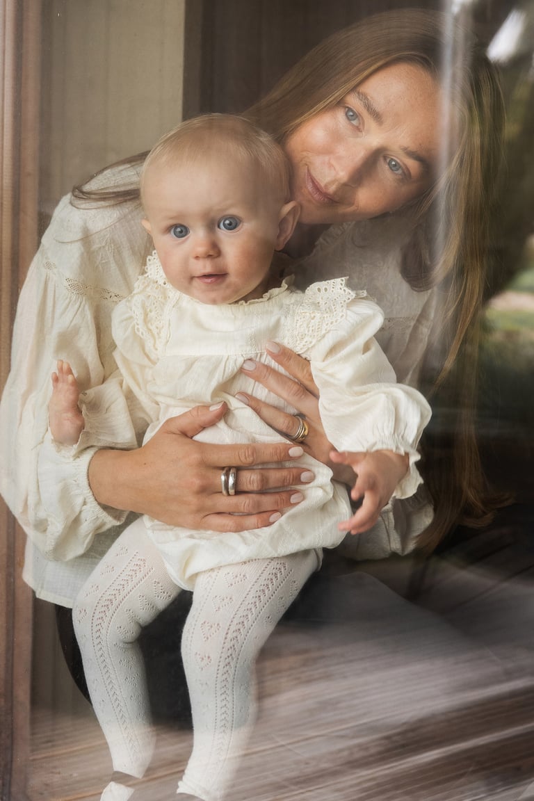 Mamma och dottern tittar ut genom fönstret klädda i Newbie kläder.