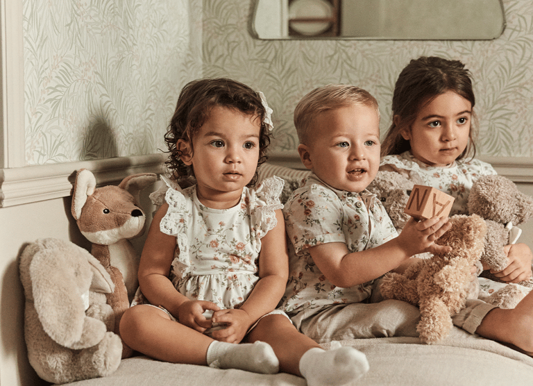 Tre barn på en soffa i blommiga kläder från Newbie.