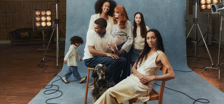 Sex personer, barn och vuxna samt en hund som står framför en backdrop.