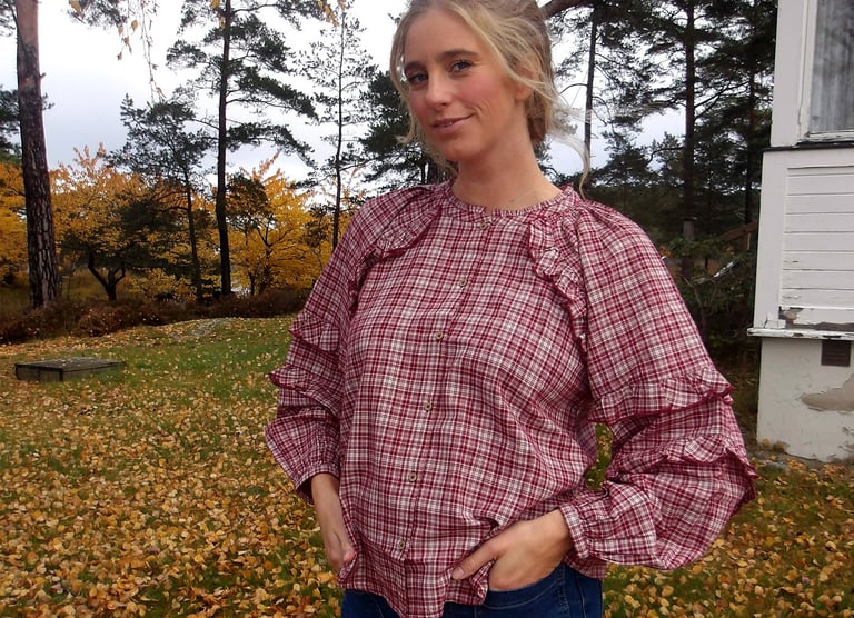 Kvinna utomhus i rutig volangblus.