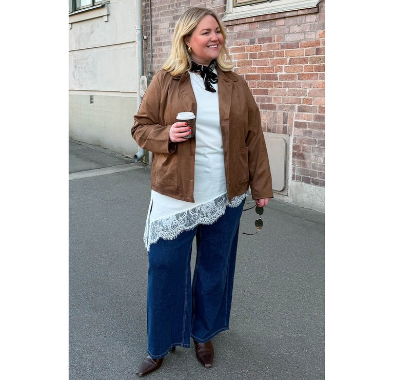 Influencern Johanna CurvesInClothes står på en gata i våriga Xlntkläder.